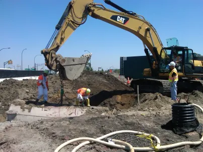 Construction workers operating an excavator at a work site under clear skies.